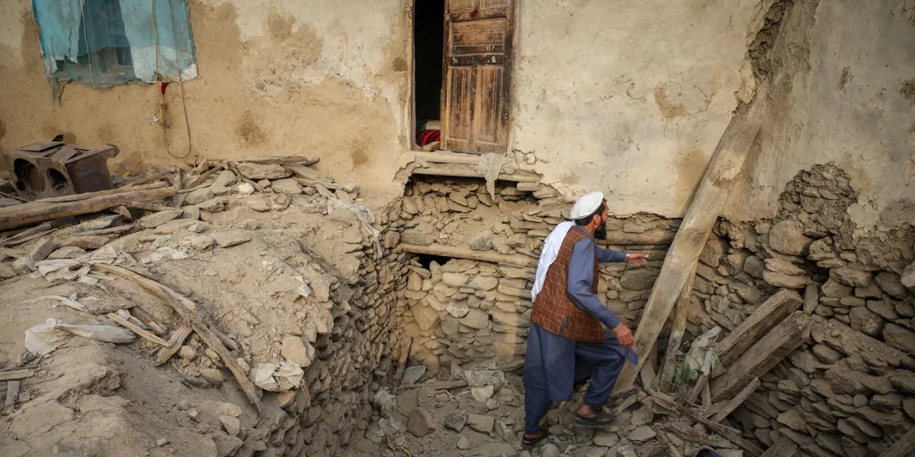 An Afghan man looks for his belongings amidst the rubble of a collapsed house after a deadly magnitude-6 earthquake that struck Afghanistan around midnight, in Dara Noor, in Jalalabad, Afghanistan