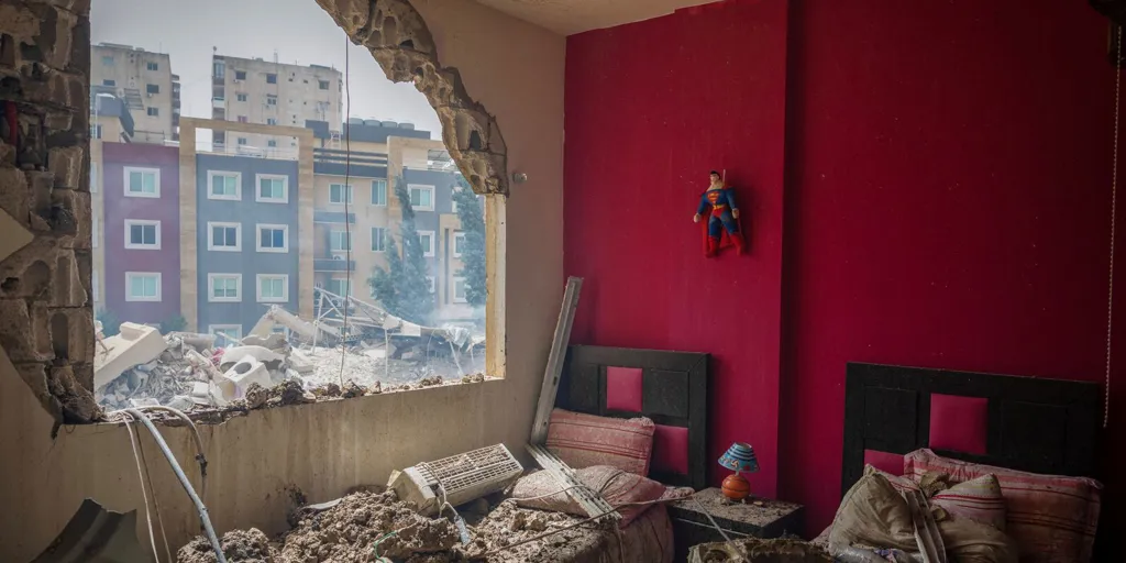 A Superman figure hangs on a wall in a red room at a house damaged by an Israeli airstrike In Tyre, Lebanon.