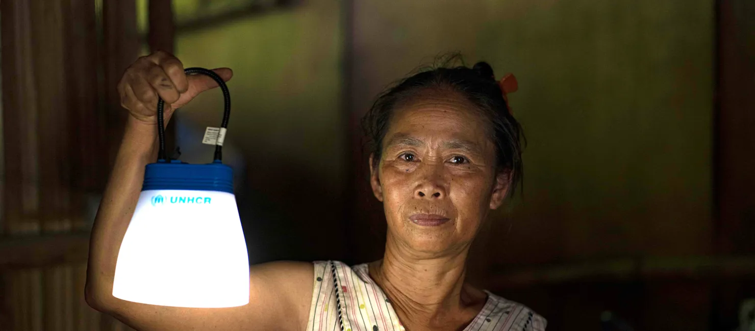 Myanmar Woman Holds Solar Lamp In Dark Shelter