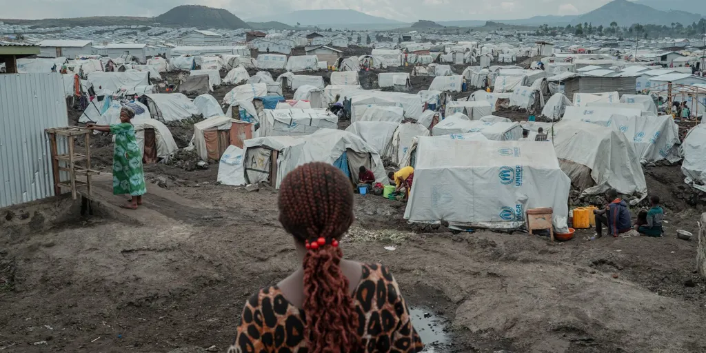 A woman looks out over tents at a crowded displacement site in eastern DRC, where Ebola is threatening lives.